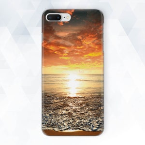 May include: A phone case with a sunset over the ocean. The sky is a vibrant orange and pink, and the water is a deep blue. The waves are crashing on the shore, and the sand is white.