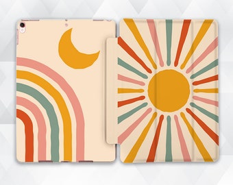 May include: A cream-colored iPad case with a rainbow, sun, and crescent moon design. The front of the case features a rainbow with pink, orange, yellow, green, and red stripes. The back of the case features a sun with yellow, orange, and red rays.