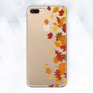 Può includere: Una custodia per telefono trasparente con sfondo dorato e un design di foglie autunnali in tonalità di rosso, arancione e giallo. La custodia è per un iPhone.