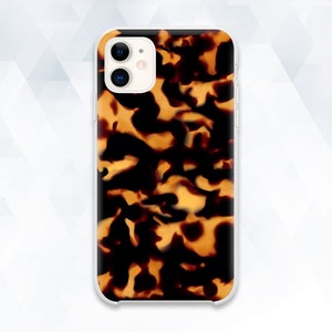 May include: A clear phone case with a tortoiseshell pattern. The case has a raised camera bump and a cutout for the phone's buttons.