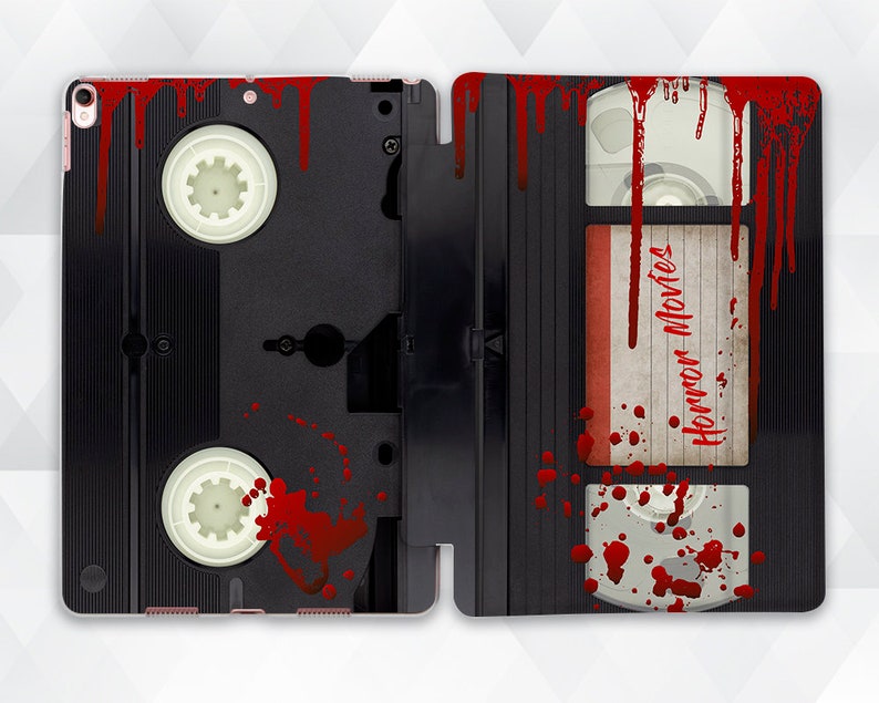 May include: A black and red VHS tape case with the words "Horror Movies" printed on the label. The case is covered in red splatters, resembling blood.