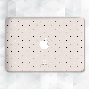 May include: A light beige laptop skin featuring a repeating pattern of small black polka dots. The centre of the skin displays a white Apple logo cutout, and the letters EG are printed in a black serif font below the logo on the surface.