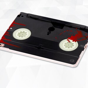 May include: A black and white VHS cassette tape case with red blood splatter. The case is designed for an iPad.