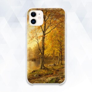Puede incluir: Una funda para teléfono con un paisaje otoñal escénico que presenta un lago, árboles con hojas amarillas y una pequeña figura en la distancia.
