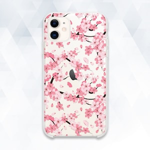 May include: A clear phone case with a pink cherry blossom design. The case has a cutout for the camera lens.