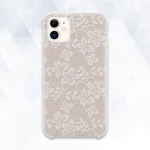 Op de afbeelding: Een transparante telefoonhoes met een delicaat, crèmekleurig bloemenkantpatroon. De hoes is ontworpen voor een smartphone, met uitsparingen voor de camera en knoppen. Het kanten ontwerp bedekt de gehele achterkant.