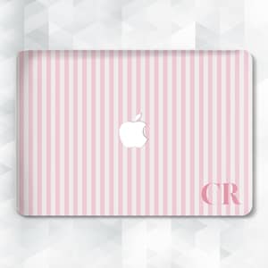 May include: A pink and white striped laptop skin with a white Apple logo. The initials "CR" are in the bottom right corner. The design features vertical stripes and a glossy finish.