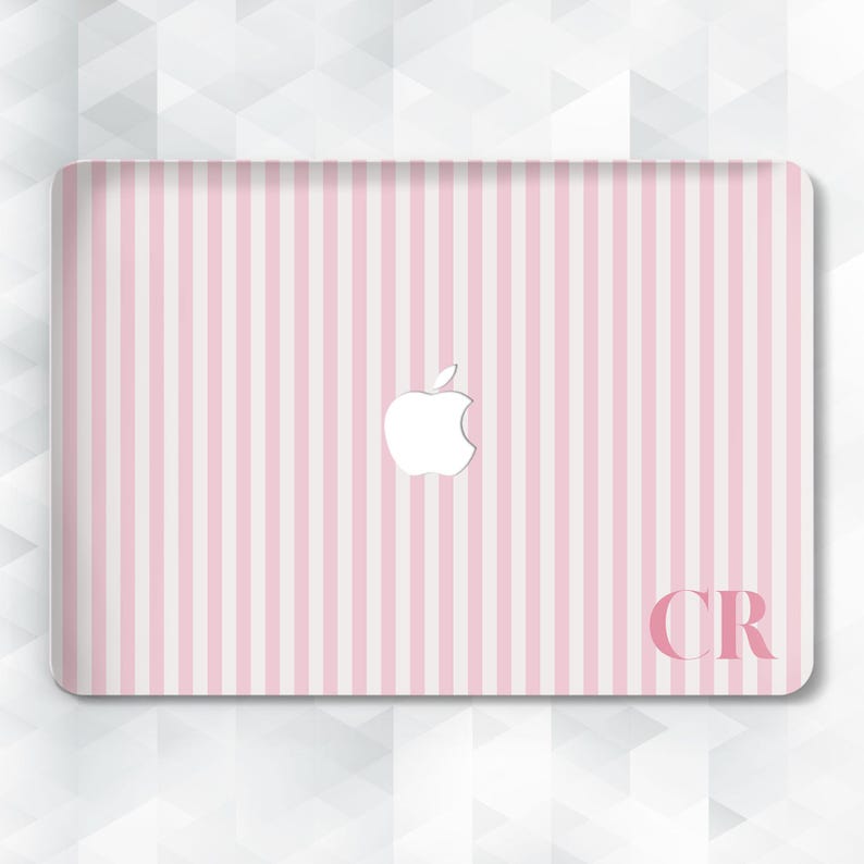 May include: A pink and white striped laptop skin with a white Apple logo. The initials "CR" are in the bottom right corner. The design features vertical stripes and a glossy finish.