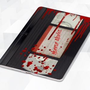 May include: A black VHS tape with a red label that says "Horror Movies" and red blood splatters on the tape.
