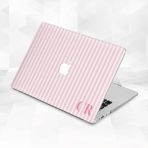 May include: A laptop with a pink and white striped design. The laptop has a white Apple logo and the initials "CR" in pink. The laptop is open, revealing the keyboard.
