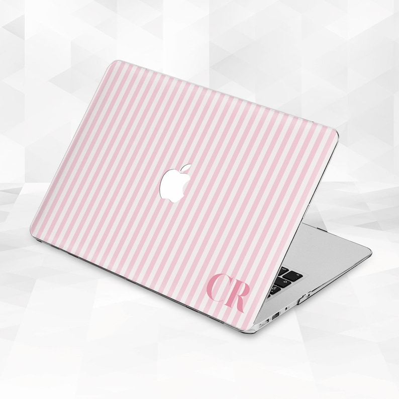 May include: A laptop with a pink and white striped design. The laptop has a white Apple logo and the initials "CR" in pink. The laptop is open, revealing the keyboard.
