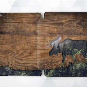 May include: A woodgrain iPad case with a silhouette of a moose with a forest inside. The moose is in the center of the case and is facing the right side of the image.