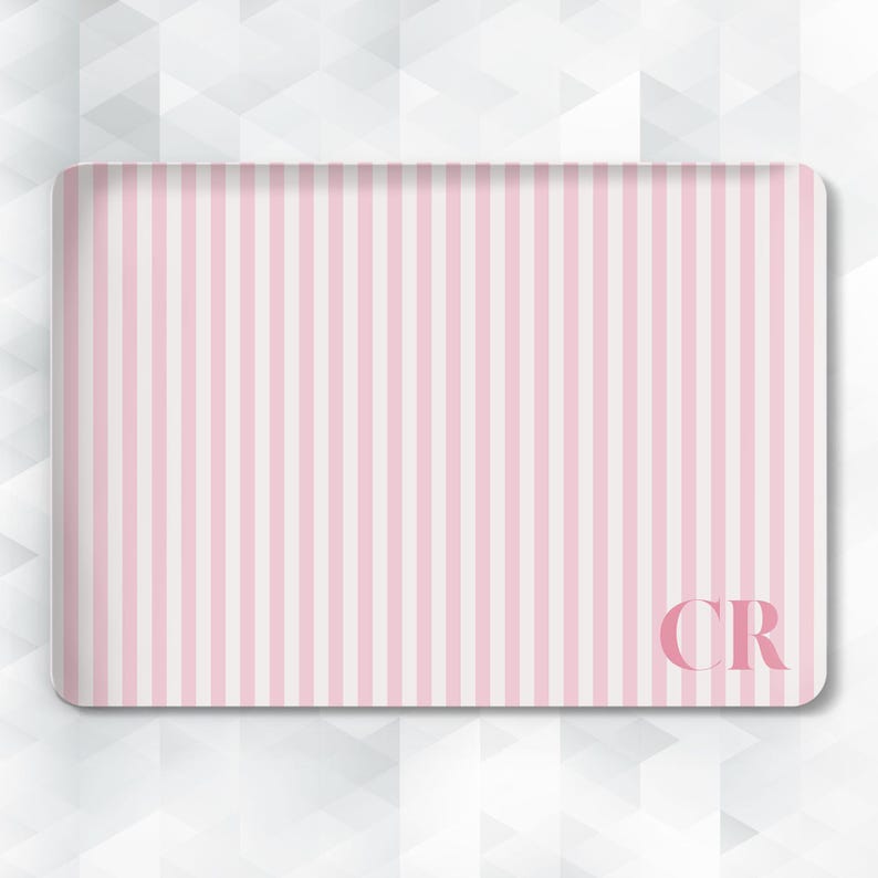 May include: Rectangular tray with a pink and white vertical stripe pattern. The tray has rounded corners and the initials "CR" in the lower right corner. The background is a white geometric pattern.