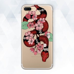 May include: A clear phone case with a red and black snake design wrapped around pink cherry blossoms. The snake has a yellow eye and a black and white pattern.