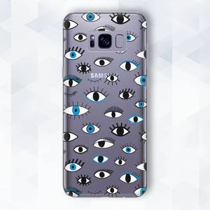 May include: A clear phone case with a pattern of blue and black eyes. The case is designed for a Samsung phone.