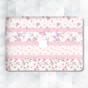 Peut inclure: Une coque d'ordinateur portable décorative avec un motif floral de roses roses et de feuilles vertes sur fond rose clair. Le design comprend des rayures horizontales de dentelle et des arrangements floraux. Le logo Apple est visible.
