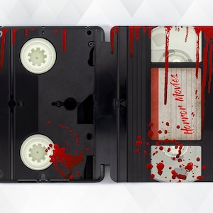 May include: A black VHS tape with red blood splatter and the words "Horror Movies" written on the label.