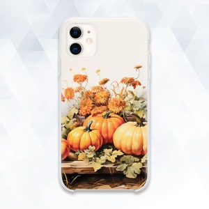 May include: A phone case with a fall-themed design featuring orange pumpkins and yellow flowers. The case is clear and shows the phone's camera lens.