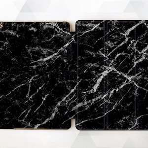 May include: Black iPad case with a white marble pattern. The case is made of a durable material and has a sleek design.