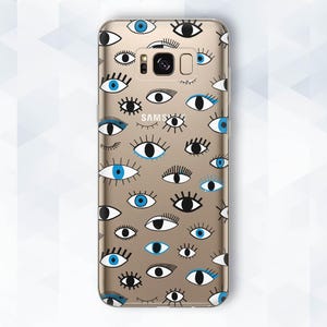 May include: A gold phone case with a pattern of blue and black eyes. The case has a Samsung logo on the back.
