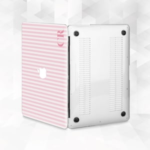 May include: A pink and white striped laptop case with the initials "CR" in a matching pink font. The case is open, revealing the white underside of the laptop. The Apple logo is visible on the case.