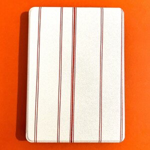 May include: White square coaster with red stripes.