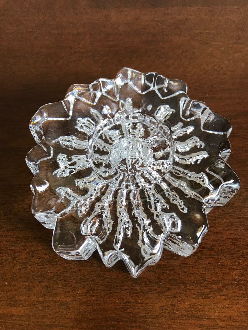 Pu&ograve; includere: Un portacandele in vetro trasparente con un design a stella. Il portacandele ha un centro rialzato per una candela e un bordo smerlato.