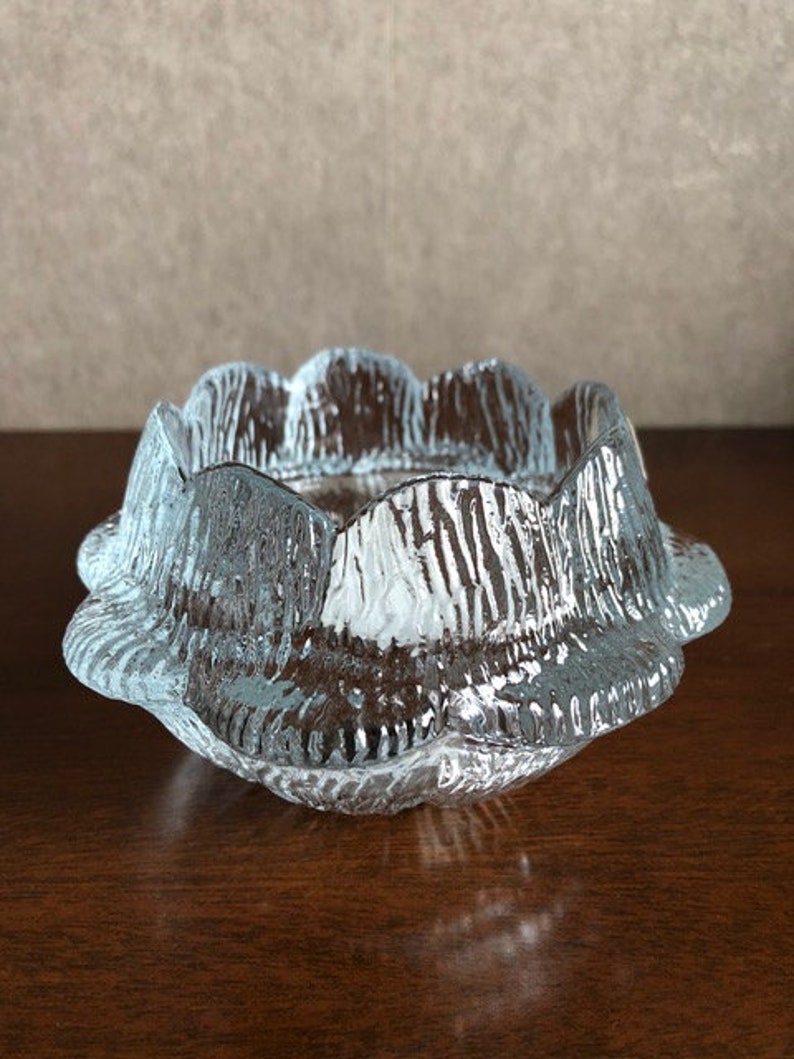 May include: A clear glass bowl with a scalloped edge and a textured surface. The bowl is designed to resemble a flower.