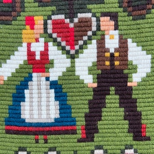 May include: Embroidered wall hanging featuring a couple in traditional folk costumes, standing under a heart-shaped design with red and brown accents. The background is green with a red and white border.