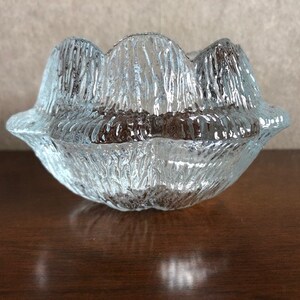 May include: A clear glass bowl with a textured, rippled surface. The bowl has a unique, organic shape resembling a flower.