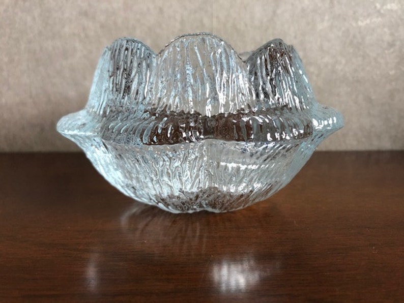 May include: A clear glass bowl with a textured, rippled surface. The bowl has a unique, organic shape resembling a flower.