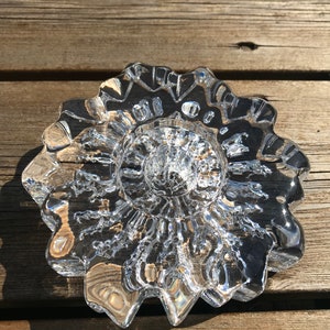 Pu&ograve; includere: Un portacandele in vetro trasparente con un design a stella. Il portacandele ha una superficie testurizzata e un centro rialzato.