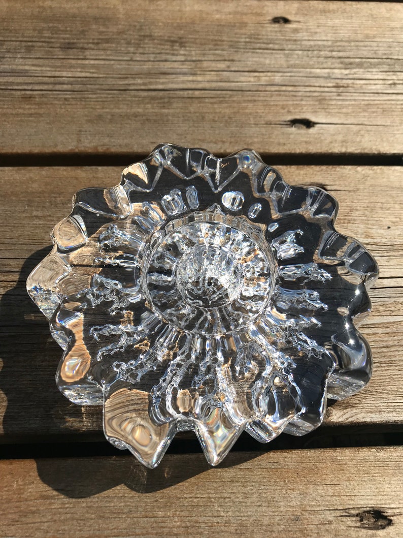 Pu&ograve; includere: Un portacandele in vetro trasparente con un design a stella. Il portacandele ha una superficie testurizzata e un centro rialzato.