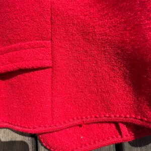 Puede incluir: Primer plano del forro de tela roja de una prenda, mostrando el detalle de la costura a lo largo del dobladillo.