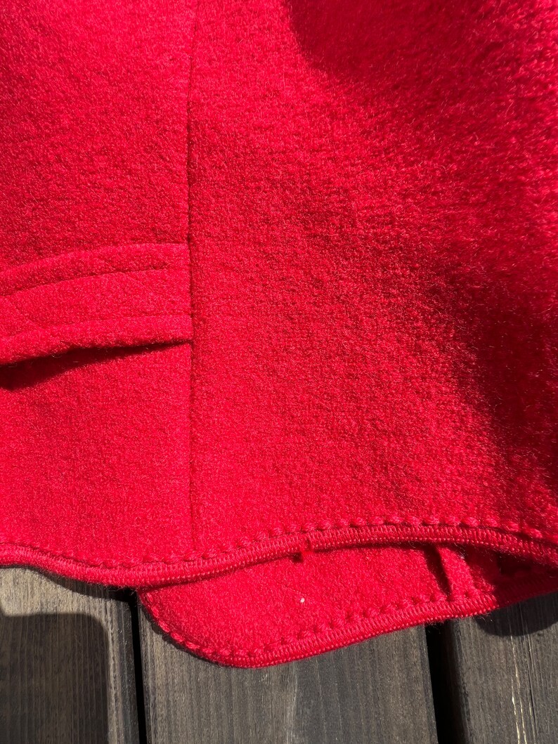 Puede incluir: Primer plano del forro de tela roja de una prenda, mostrando el detalle de la costura a lo largo del dobladillo.