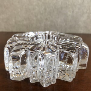 Pu&ograve; includere: Un portacandele in vetro trasparente con un design a forma di stella. Il portacandele ha una superficie testurizzata e un'apertura rotonda al centro.