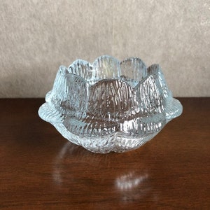 May include: A clear glass bowl with a textured, wavy design. The bowl has a scalloped edge and is perfect for holding small items.