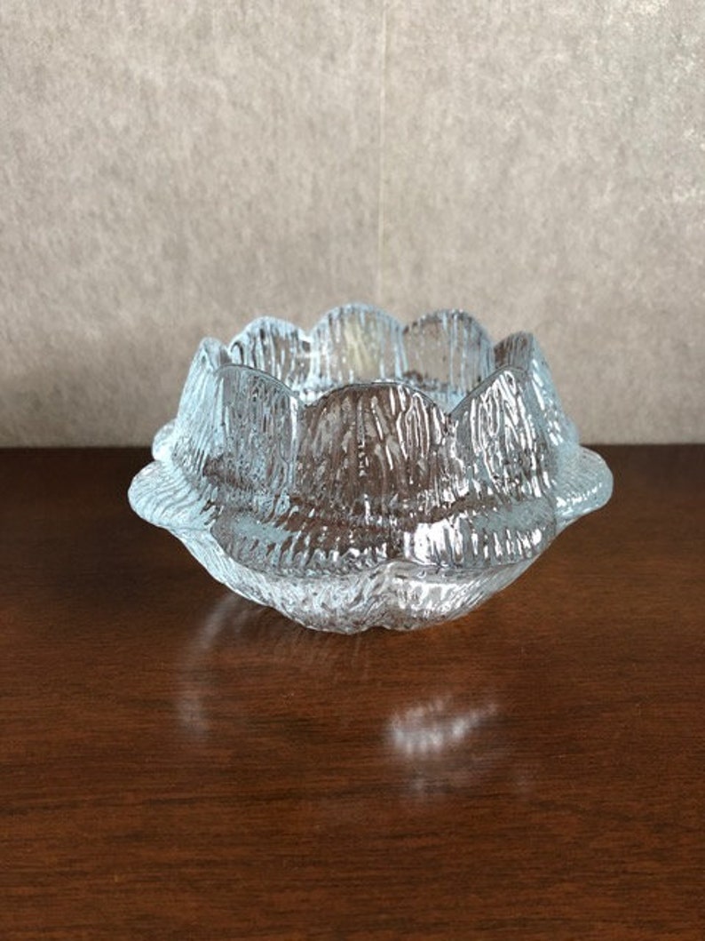 May include: A clear glass bowl with a textured, wavy design. The bowl has a scalloped edge and is perfect for holding small items.
