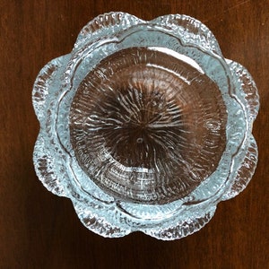 May include: A clear glass bowl with a scalloped edge and a textured surface. The bowl is round and has a diameter of approximately 10 inches.