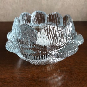 May include: A clear glass bowl with a scalloped edge and a textured surface. The bowl is designed to resemble a flower.