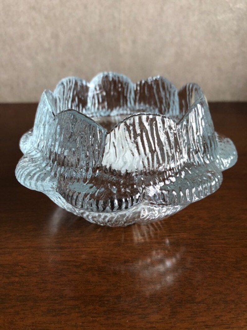 May include: A clear glass bowl with a scalloped edge and a textured surface. The bowl is designed to resemble a flower.