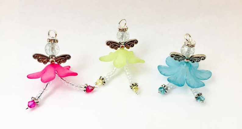 May include: Three beaded angel ornaments with wings, each with a different colored skirt: pink, yellow, and blue.