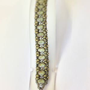 May include: A green and gold beaded bracelet with a heart-shaped charm.