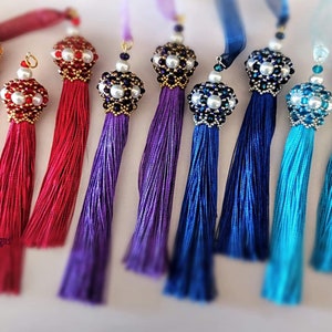 Può includere: Un set di dieci nappine colorate con perline e dettagli in perle. Le nappine sono realizzate in seta e sono disponibili in una varietà di colori, tra cui arancione, rosso, viola, blu e turchese.