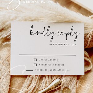 May include: A wedding RSVP card with the words "kindly reply" in elegant script. The card includes checkboxes for acceptance or regret, and a line for the number of guests. A gold wax seal and stamp are also visible.