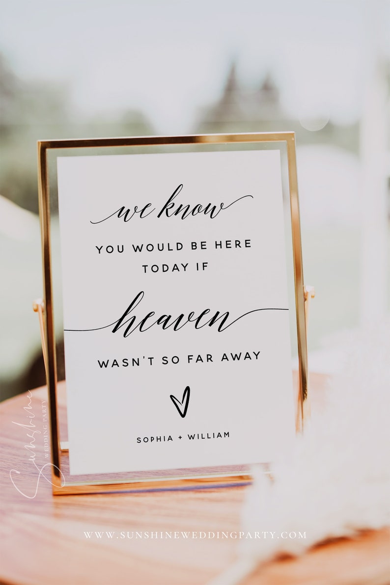 Peut inclure: Une pancarte blanche avec du texte noir dans un cadre dor&eacute;. La pancarte indique "we know you would be here today if heaven wasn't so far away." Un petit c&oelig;ur se trouve sous le texte. Les noms "Sophia + William" sont en bas de la pancarte. La pancarte est pos&eacute;e sur une table en bois.