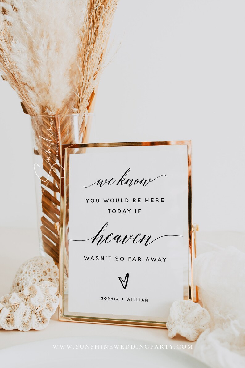 Peut inclure: Une pancarte dor&eacute;e encadr&eacute;e avec le texte "we know you would be here today if heaven wasn't so far away" avec un c&oelig;ur et les noms Sophia et William en dessous. La pancarte est pos&eacute;e sur une table avec un vase de pampas s&eacute;ch&eacute;es et du corail.