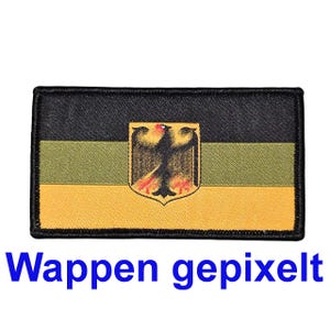 Może przedstawiać: Prostokątna naszywka z czarną obwódką i trójkolorowym wzorem w kolorze oliwkowym i żółtym. Herb z czarnym orłem jest umieszczony na środku naszywki. Tekst "Wappen gepixelt" jest wyświetlany na dole na niebiesko.