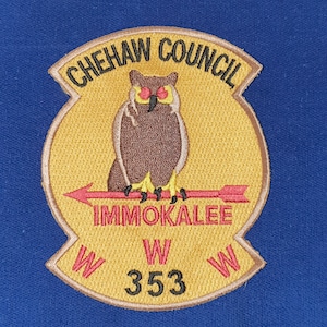 Puede incluir: Un parche bordado amarillo y marrón con el texto "Chehaw Council Immokalee W 353 W" y un búho marrón con ojos rojos.