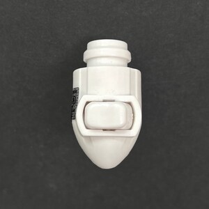 Op de afbeelding: Witte plastic lichtschakelaar met een enkele wipschakelaar. De schakelaar heeft een afgerond, kogelvormig ontwerp.